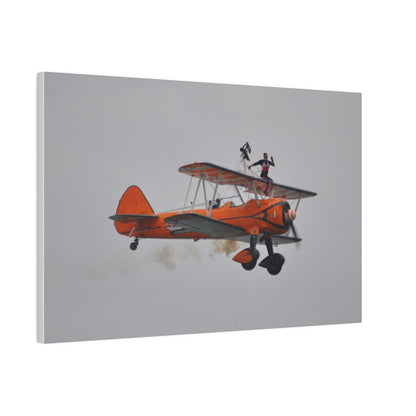 Single Wing Walker Flying From The Left, Front View Much Closer, Person Sitting On The Wing Without The Harness Looking Towards Us With Smoke, Matte Canvas, Stretched, 0.75" - The Trio Synergize Group