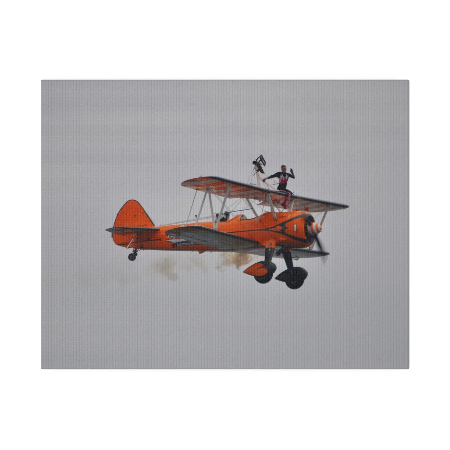 Single Wing Walker Flying From The Left, Front View Much Closer, Person Sitting On The Wing Without The Harness Looking Towards Us With Smoke, Matte Canvas, Stretched, 0.75" - The Trio Synergize Group